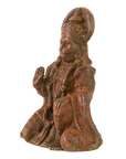 A carved figurine of a seated Hanuman, shown alone on a plain white background. The figure wears an ornate and detailed robe, with a warm reddish-brown patinated surface and darker weathered areas.