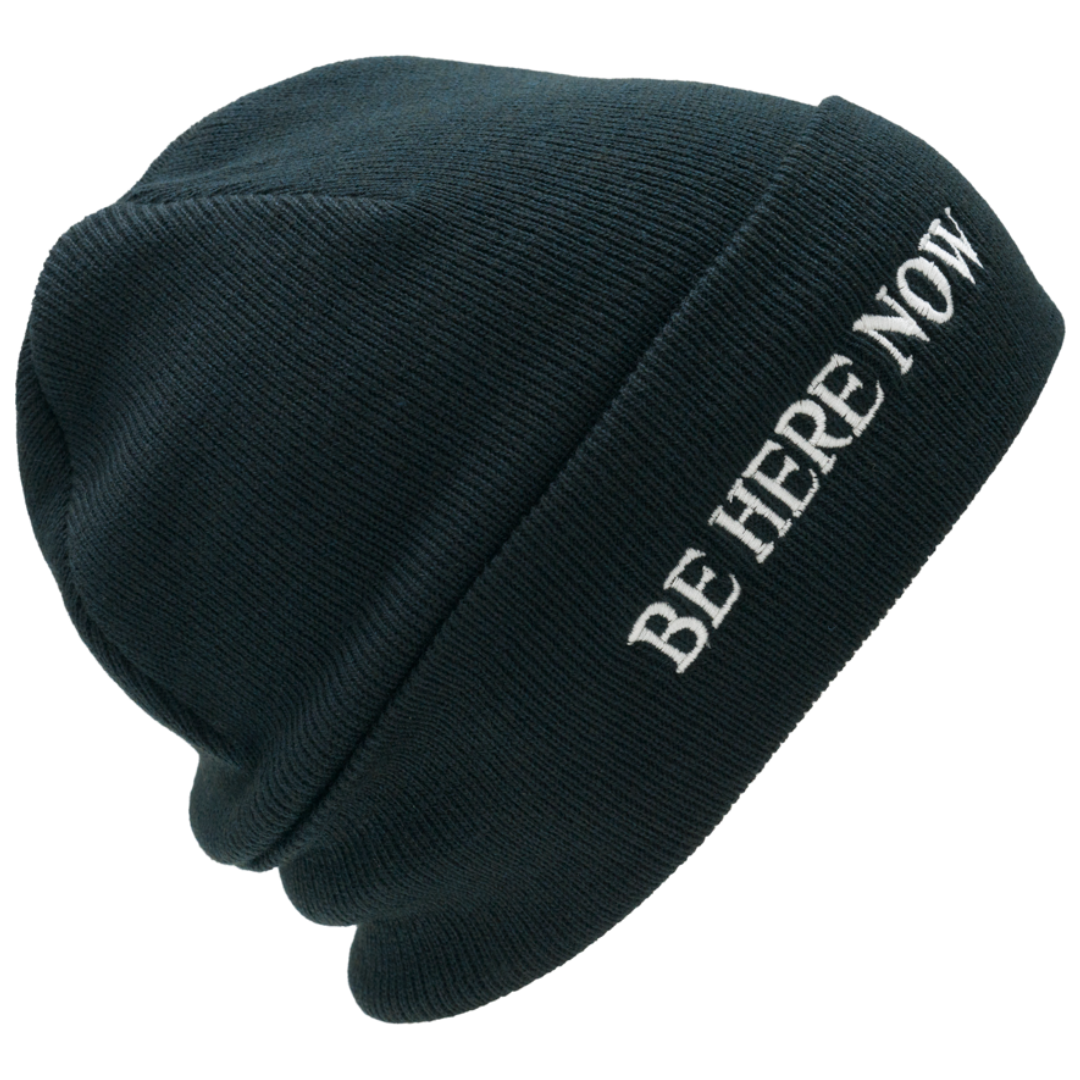 Black beanie with 'BE HERE NOW' text on a white background
