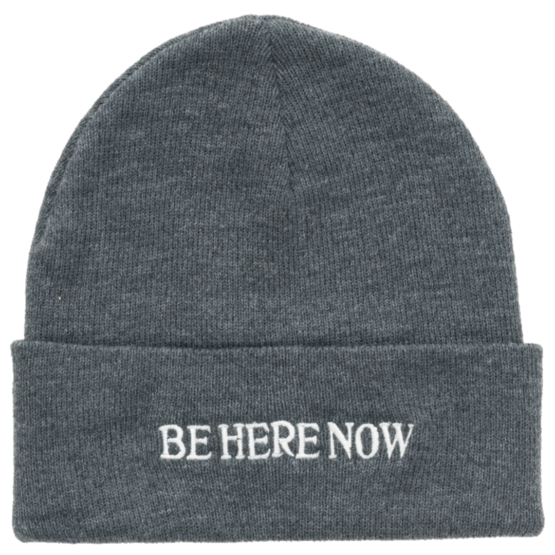 Gray beanie with 'BE HERE NOW' text on a white background