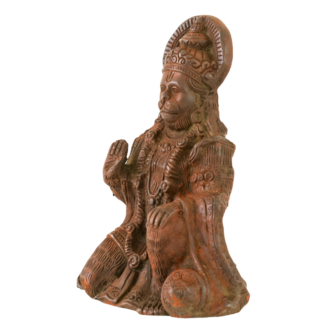 A carved figurine of a seated Hanuman, shown alone on a plain white background. The figure wears an ornate  and detailed robe, with a warm reddish-brown patinated surface and darker weathered areas.