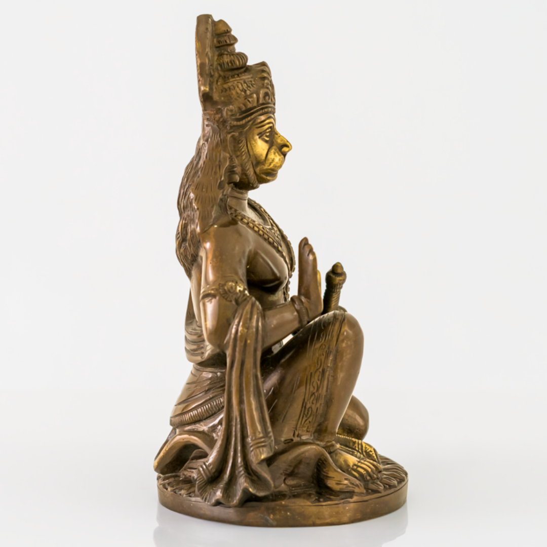 A bronze-finished seated Hanuman statue with gold-painted facial features and highlights, shown in profile against a clean white background.