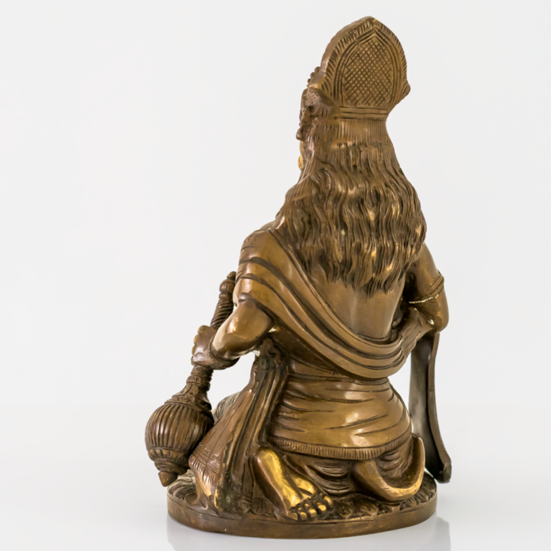 A bronze-colored religious figurine of a kneeling Hanuman, shown from the back, on a plain white background.