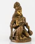 A bronze-finished statue of Lord Hanuman in a seated pose, featuring gold-plated accents on the face, chest, and jewelry, set against a plain white background.