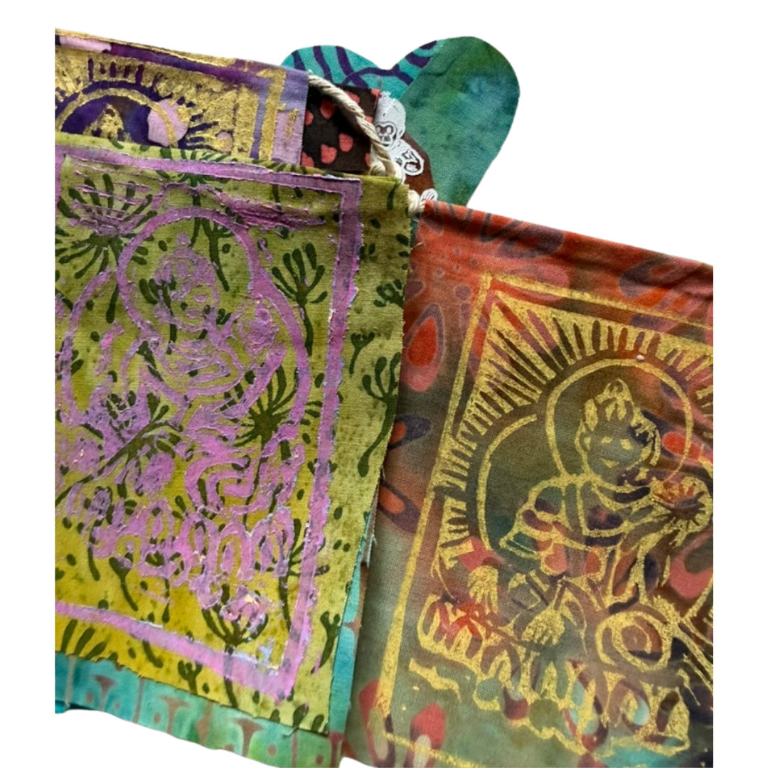 Two folded hand-woven fabric prayer flags with traditional Indian motifs, featuring metallic gold foil printing on a green, purple, and orange base.