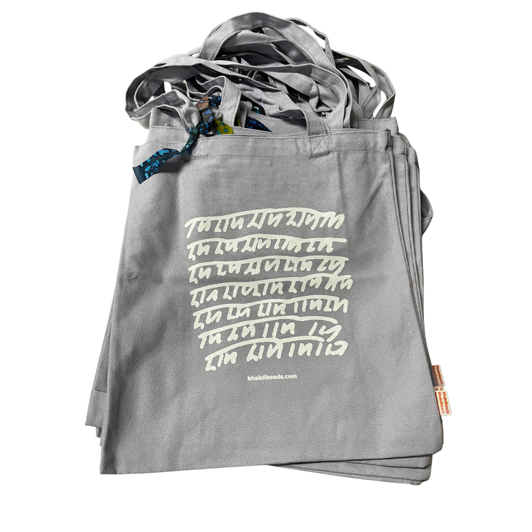 A stack of gray fabric tote bags with white hand-drawn style text printed on the front, photographed on a clean white background.