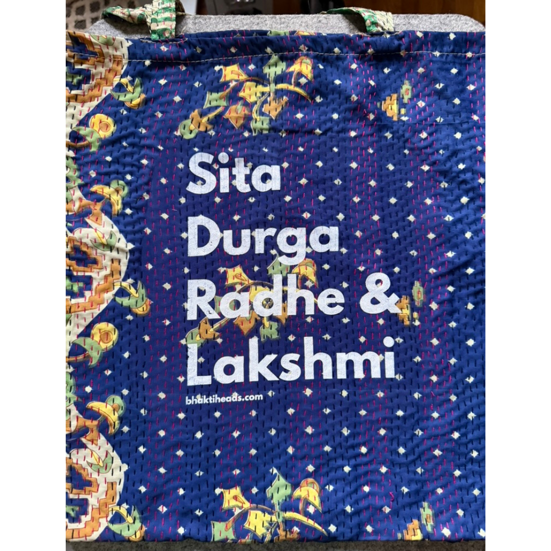 A blue quilted fabric tote bag with a kantha-style floral border and white text reading 'Sita Durga Radhe &amp; Lakshmi' with the website 'kikistheobs.com' printed below.