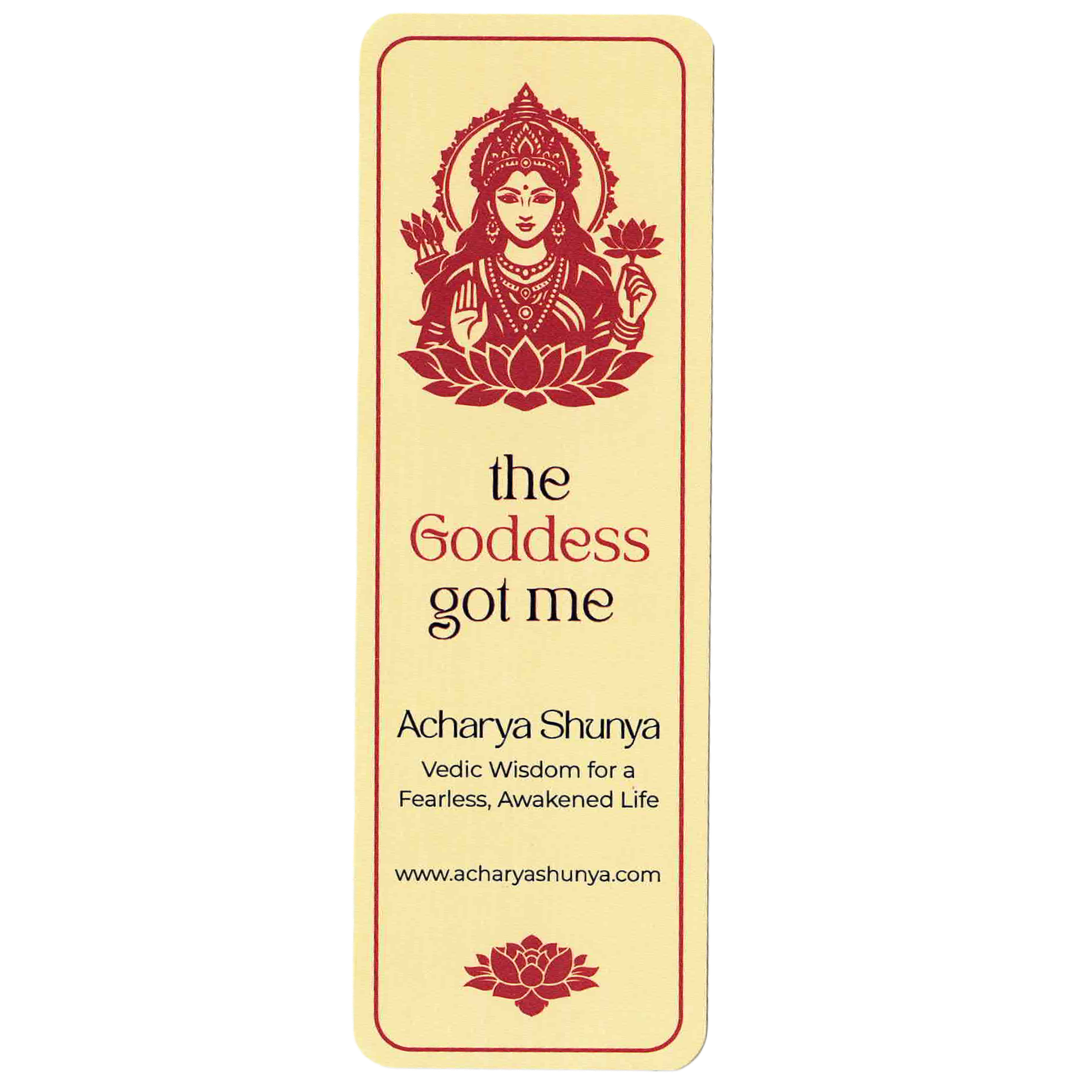 A tall, narrow cream-colored card or bookmark with a red illustration of a goddess on a lotus and the text 'the Goddess got me', 'Acharya Shunya', and 'www.acharyashunya.