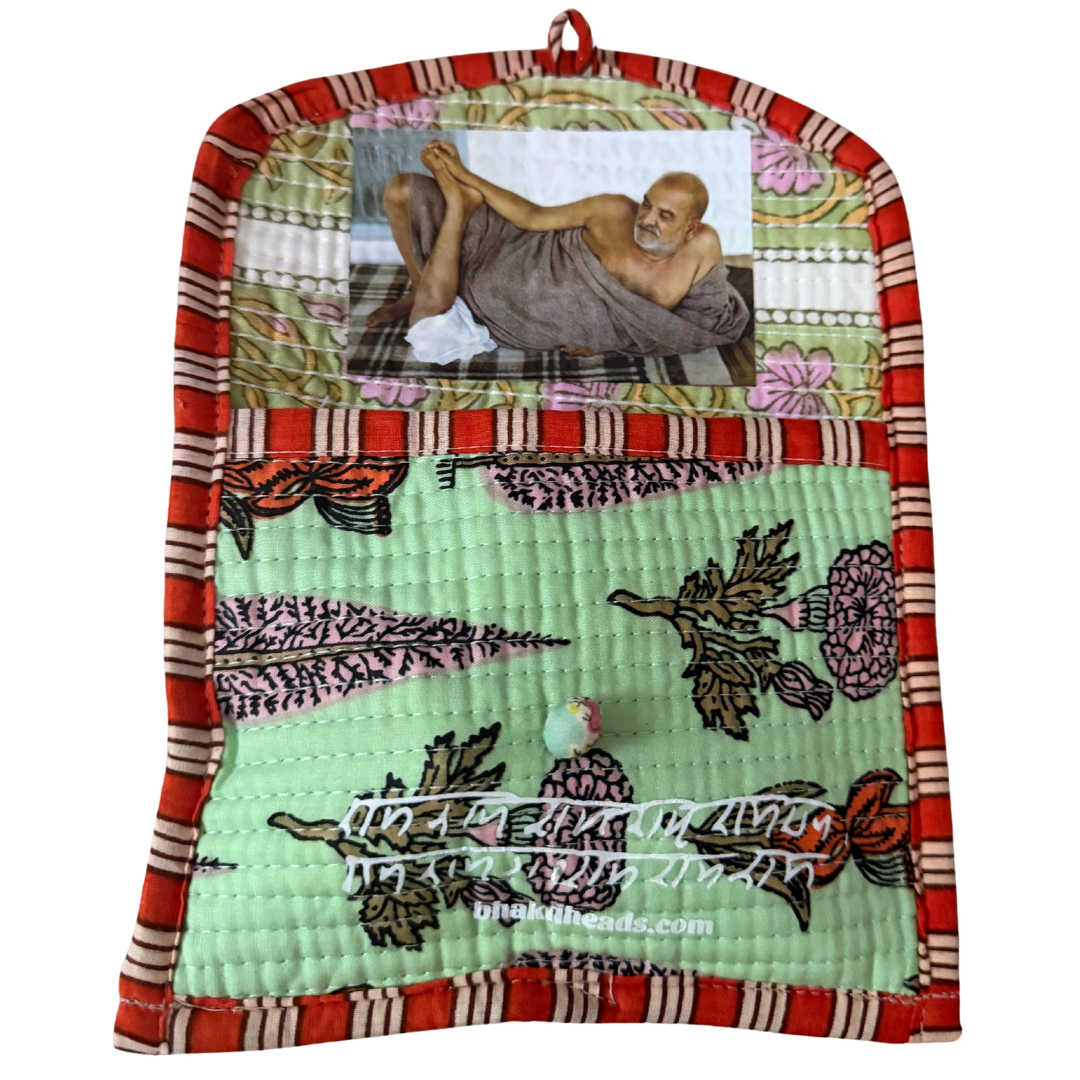 A handmade quilted fabric wall hanging or pocket with a red and cream striped border, a mint green floral patterned lower section, and a top panel featuring a photo of Mahatma Gandhi. A small wooden bead hangs from the bottom center.